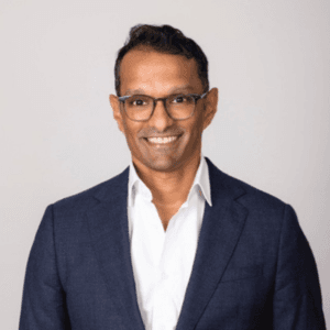 Ravi Sharma smiling, wearing glasses and a navy blazer.